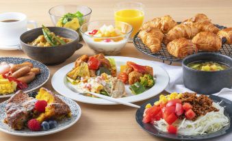 a table is filled with a variety of breakfast dishes , including salads , fruit , and pastries at Candeo Hotels Omiya