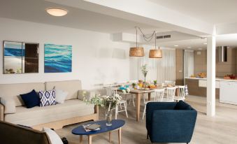 a modern living room and dining area with a couch , chairs , and a table at Pierre & Vacances Blanes Playa