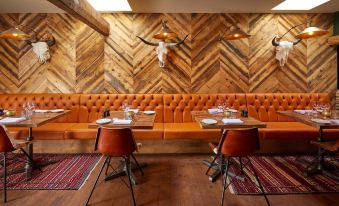 a restaurant with wooden walls and a large orange booth , featuring a wooden table and chairs at The Bull Hotel