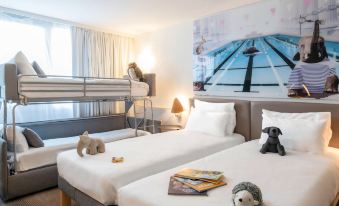 a room with two beds , one of which is a bunk bed , and two stuffed animals on the beds at Novotel Dijon Sud