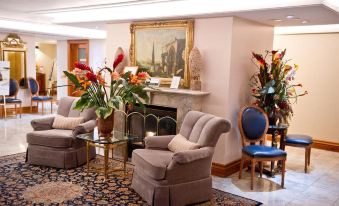 a living room with a fireplace , chairs , and a vase of flowers on the mantle at The Waterside Inn