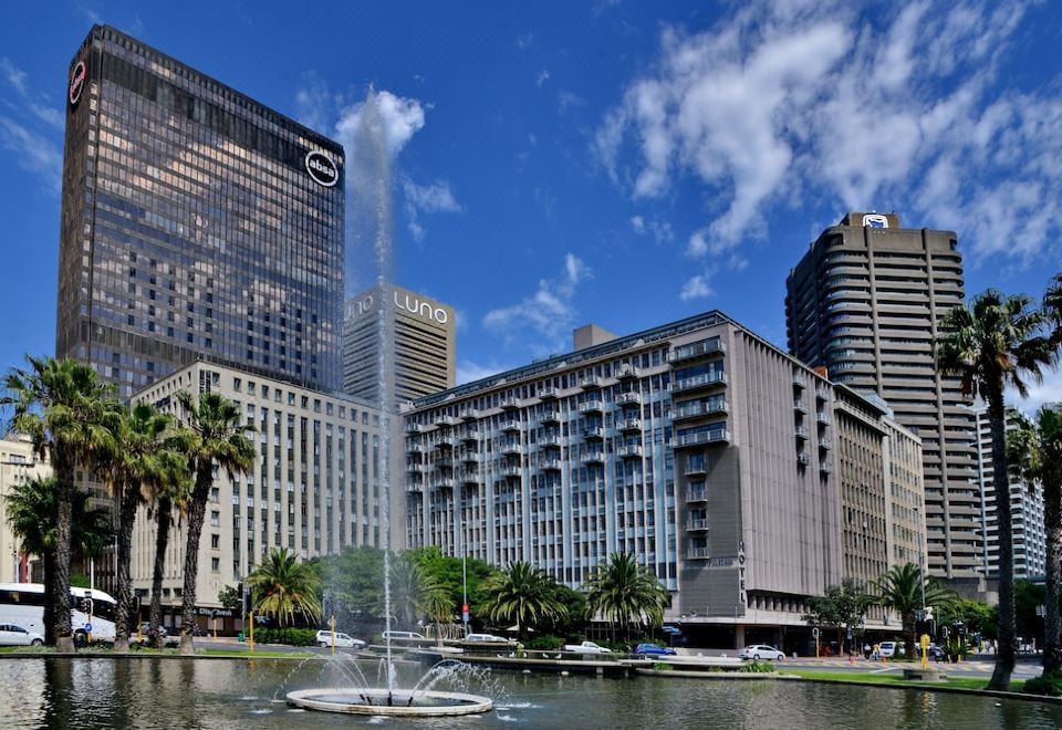 a fountain in a city park with tall buildings in the background , creating a picturesque scene at Fountains Hotel