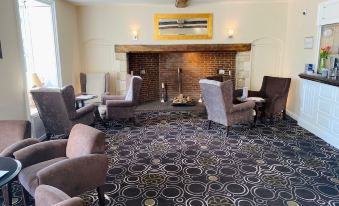 a cozy living room with a fireplace , several chairs , and a rug on the floor at Best Western Priory Hotel