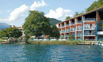 a blue and orange building is situated on the shore of a lake , with trees in the background at Hotel l'Approdo