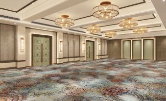 a large room with a colorful carpet and multiple doors is illuminated by hanging light fixtures at Ekante Bliss Tirupati - Ihcl SeleQtions