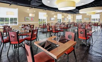 a large , modern restaurant with multiple dining tables and chairs arranged in an open space at DoubleTree by Hilton Sunrise - Sawgrass Mills