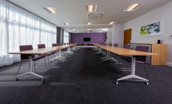 a large conference room with multiple rows of tables and chairs arranged in a long line at Hampton by Hilton Exeter Airport