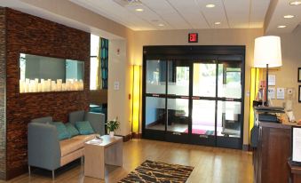 a modern hotel lobby with a check - in desk and a large window , allowing natural light to enter the room at Hampton Inn & Suites by Hilton Stroudsburg Pocono Mountains