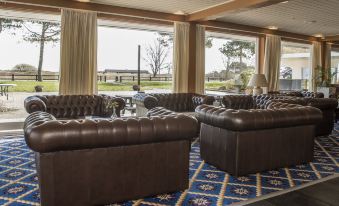 a living room with brown leather couches and chairs arranged around a coffee table , creating a cozy atmosphere at Hotel Marina