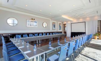 a conference room with a long table , blue chairs , and water bottles set up for a meeting at Hyatt House Jersey City