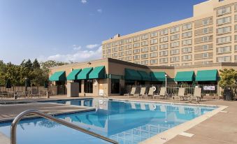 a large hotel with a swimming pool surrounded by lounge chairs and umbrellas , providing a relaxing atmosphere for guests at DoubleTree by Hilton Hotel Grand Junction