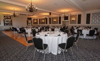 a large dining room with several round tables covered in white tablecloths , creating a formal atmosphere at New Inn Hotel