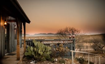 "a desert landscape with a sign that reads "" deon mountain views "" in the foreground , and cacti and mountains in the background" at Tombstone Monument Guest Ranch
