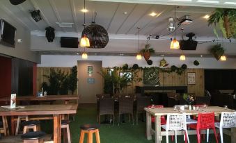 a restaurant with wooden tables and chairs , a green carpet , and hanging lights on the ceiling at Poenamo Hotel