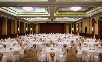 a large banquet hall is set up with tables and chairs , all covered in white tablecloths at Ajman Hotel by Blazon Hotels