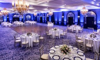 a large banquet hall with multiple round tables set up for a formal event , possibly a wedding reception at The Madison Hotel