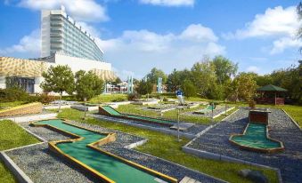 a miniature golf course surrounded by grass and trees , with a building in the background at Ana Hotels Europa Eforie Nord