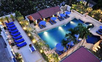 a large outdoor pool surrounded by lounge chairs and umbrellas , creating a relaxing atmosphere for guests at Tara Angkor Hotel