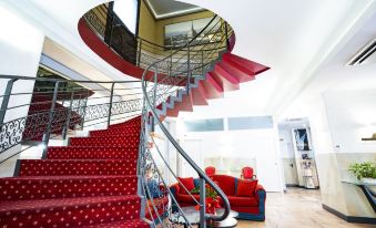 a spiral staircase in a room with red carpeting and white walls , leading to the second floor at Hotel Plaza