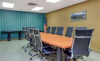 a conference room with a long wooden table and multiple chairs , along with an american flag on the wall at Comfort Suites Oakbrook Terrace Near Oakbrook Center