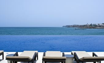a row of lounge chairs is set up next to a large body of water at Radisson Blu Hotel, Dakar Sea Plaza