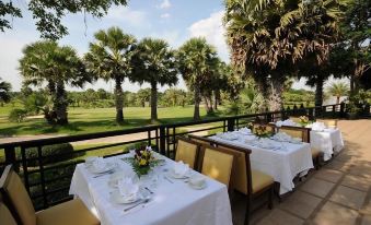 a restaurant with tables set up on a patio overlooking a golf course , creating a pleasant atmosphere at Suwan Golf and Country Club