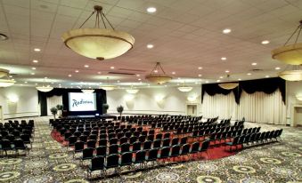 a large conference room with rows of chairs arranged in a semicircle , and a projector screen on the wall at Penn Harris Hotel Harrisburg, Trademark by Wyndham