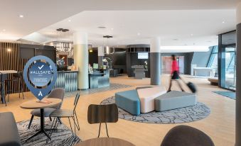 a modern hotel lobby with a blue and gray seating area , multiple couches , chairs , and a reception desk at Novotel Marne la Vallee Noisy le Grand Hotel