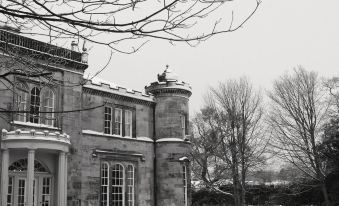 a black and white photo of a stone house with a balcony and trees in the background at Kincaid House Hotel