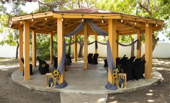 a wooden gazebo with draped fabric and flowers is set up for a wedding ceremony at Solace by the Sea