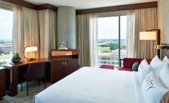 a hotel room with a king - sized bed , a desk , and a window overlooking a beautiful view at Renaissance Dallas at Plano Legacy West Hotel