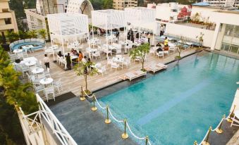 a rooftop bar with a pool , umbrellas , and tables set up for guests to enjoy drinks and socialize at Hotel Centre Point