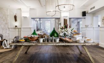 a long dining table filled with a variety of food items , including bowls , cups , and plates at Watsons Bay Boutique Hotel