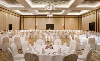 a large , empty banquet hall with numerous round tables and chairs set up for an event at Djibouti Palace Kempinski