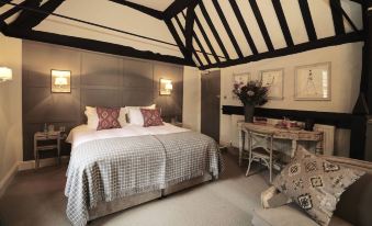 a bedroom with a large bed , a chair , and a table in the corner of the room at The Bull Hotel