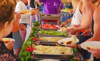 a group of people are gathered around a buffet table with various food items , including plates of food at Likuri Island Resort Fiji