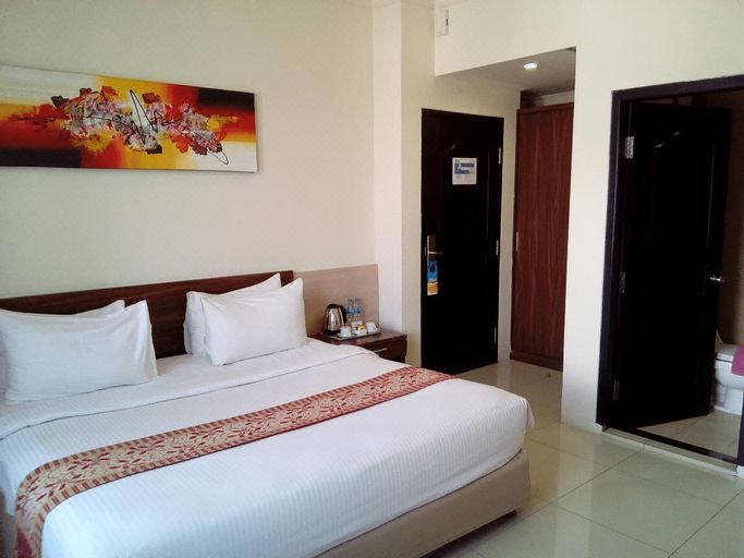 a large bed with white linens is in a room with a door and an abstract painting on the wall at Hotel Marina Bima