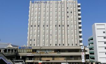 "a modern building with the word "" nippon "" on its side , surrounded by a bustling city street" at Meitetsu Inn Kariya