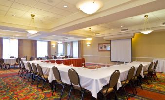 a conference room with a large table surrounded by chairs and a projector screen on the wall at Hilton Garden Inn Wooster