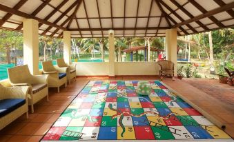 a colorful play area with a large , colorful game mat in the center , surrounded by comfortable seating and outdoor furniture at Poovar Island Resort