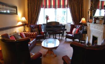 a well - decorated living room with a grand piano in the center , surrounded by couches and chairs at Woodlands