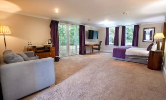 a spacious living room with a large window and sliding glass door leading to an outdoor area at Woodland Manor Hotel