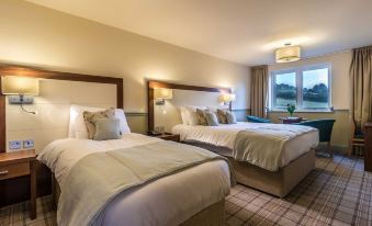 a hotel room with two beds , one on the left side and the other on the right side of the room at Damson Dene Hotel