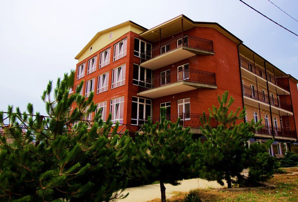 a modern red apartment building surrounded by green trees and bushes , creating a picturesque setting at Well Hotel and Spa