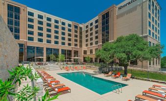 a large hotel with a pool surrounded by chairs and umbrellas , providing a relaxing atmosphere at Sheraton Austin Georgetown Hotel & Conference Center
