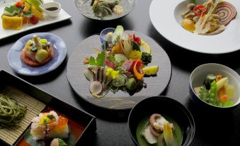 a dining table with a variety of dishes , including sushi and other japanese food , placed on it at Mizno Hotel