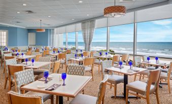 a large dining room with multiple tables and chairs , all set for a meal , overlooking the ocean at Hilton Myrtle Beach Resort