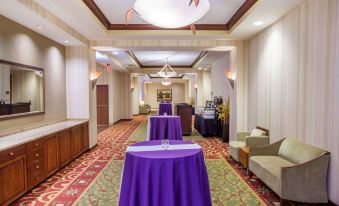 a hotel lobby with several tables covered in purple tablecloths , creating a festive atmosphere for guests at Sonesta Milwaukee West Wauwatosa