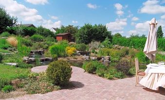a beautiful garden with a brick walkway surrounded by various plants and flowers , creating a serene and inviting atmosphere at La Cote d'Or