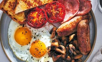 a large plate filled with a variety of food items , including eggs , bacon , sausage , mushrooms , and toast at The Anchorage Hotel